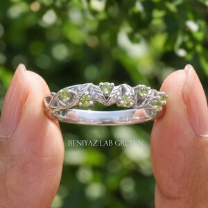 Nature inspired green gemstone ring shown from the side, highlighting the decorative vine shank and peridot settings.