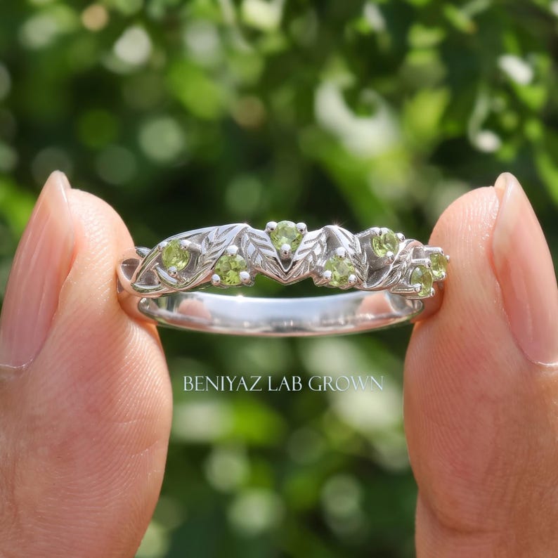 Nature inspired green gemstone ring shown from the side, highlighting the decorative vine shank and peridot settings.