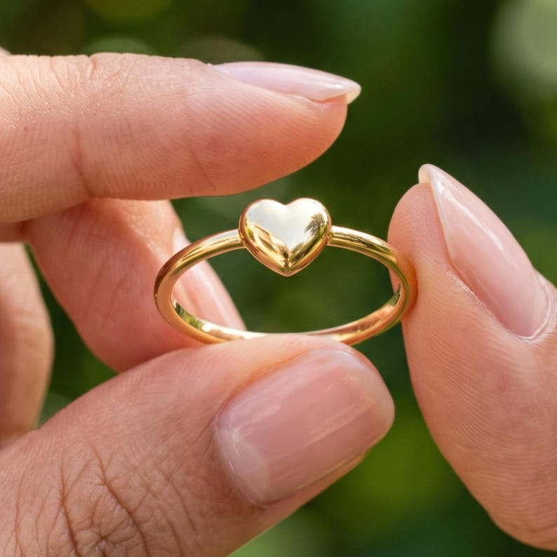 Angled close view of puffy heart ring with smooth raised heart and stackable minimalist band.