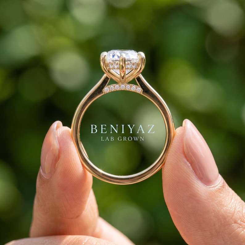 Close up hand held view of a marquise lab grown diamond engagement ring with vintage scrollwork yellow gold band.