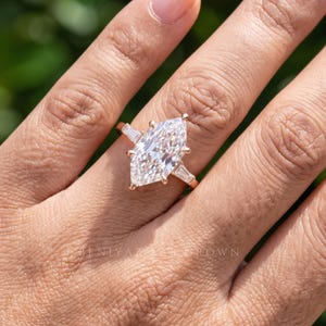 Lifestyle close up of Dutch marquise engagement ring worn on finger with elongated lab grown diamond center and side accents