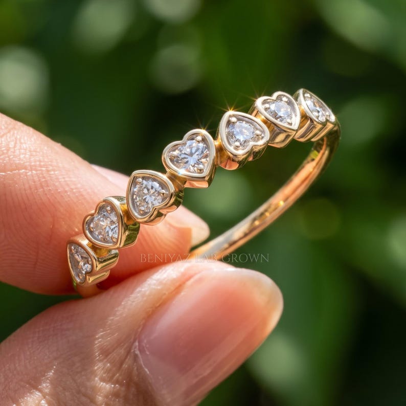 Heart eternity band with a row of heart cut lab grown diamonds in heart shaped bezels on a slim gold band
