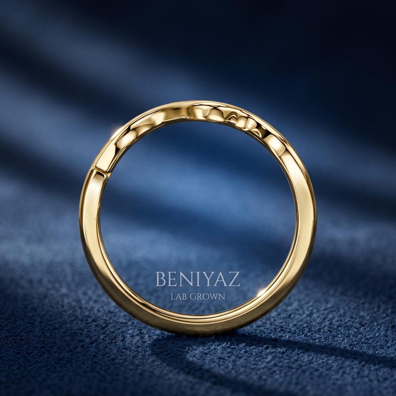 Angled close up of a minimalist yellow gold wishbone wedding band showing its smooth curved nesting design.