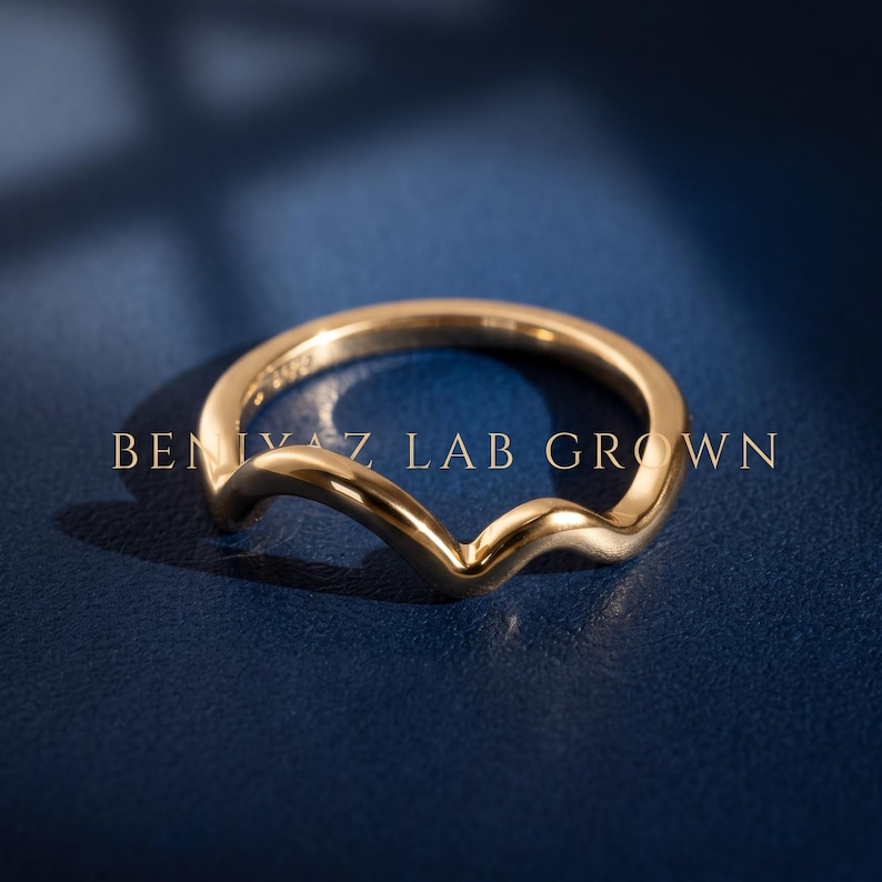 Curved V contour wedding band in yellow gold worn with an engagement ring, showing the 2mm chevron nesting shape on hand.