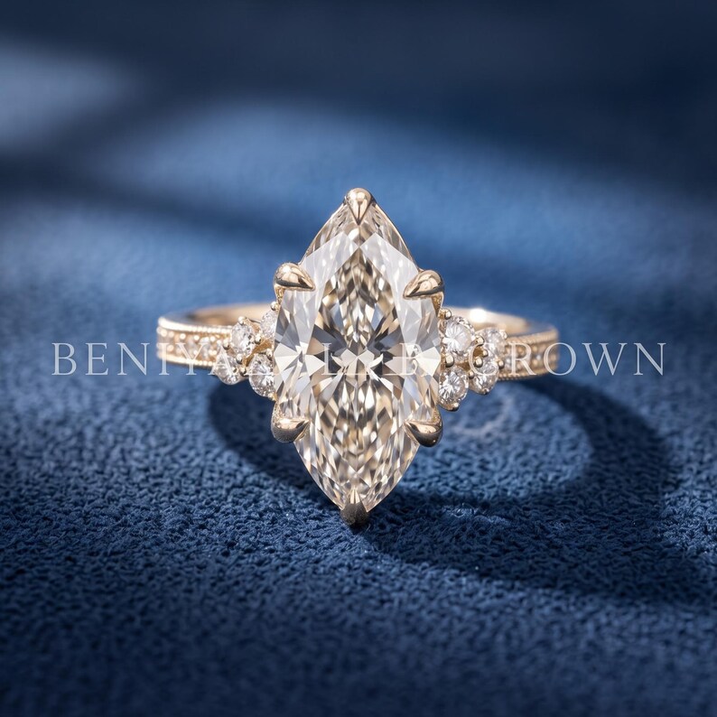 Front angled view of a 3 CT marquise diamond engagement ring in yellow gold on a dark blue luxury background.