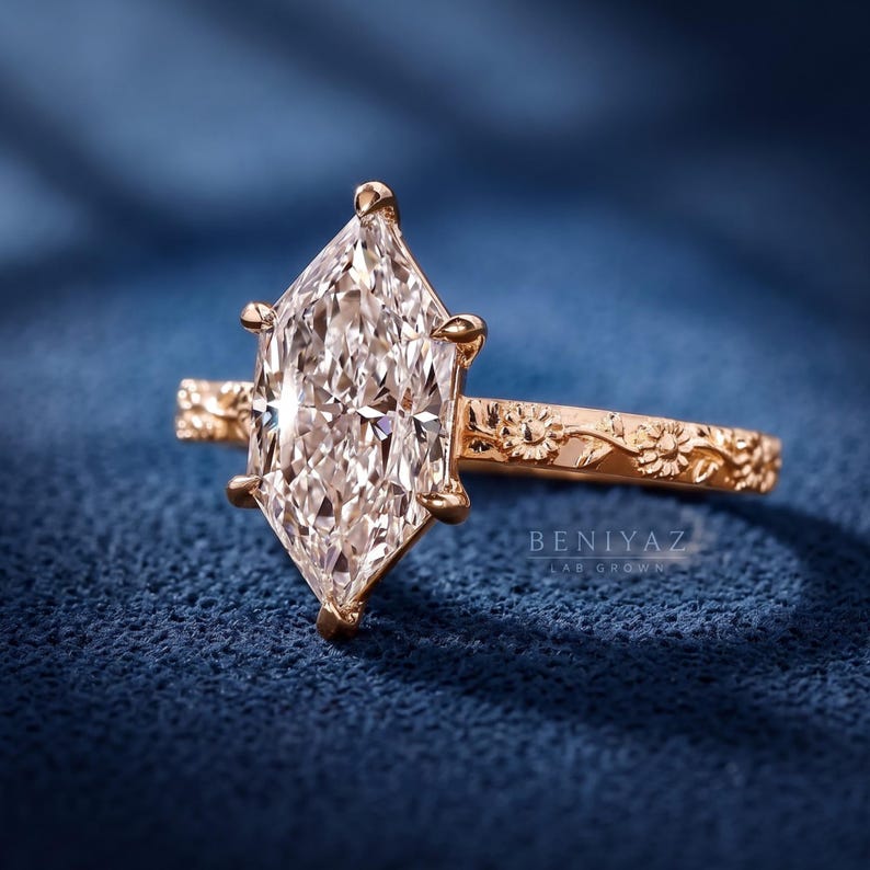 Angled front view of a marquise lab grown diamond engagement ring showing the pointed center and floral gold shank.