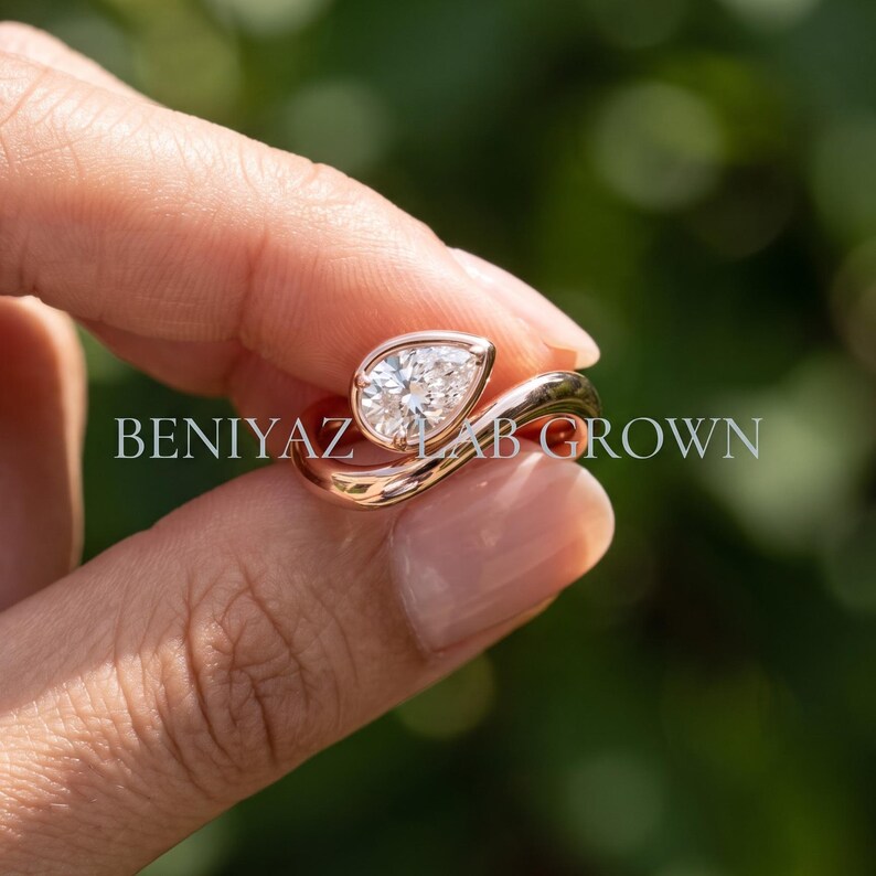 Pear lab grown diamond bypass engagement ring worn on hand, showing the scale and bold sculptural silhouette.
