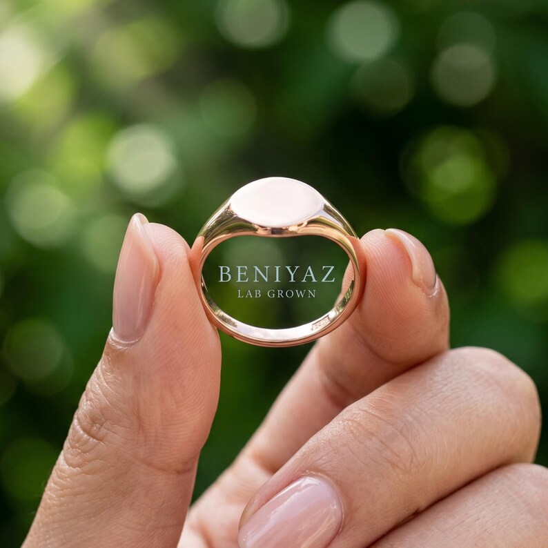 Inside view of minimalist round signet ring held by hand showing smooth interior, tapered band and plain polished construction