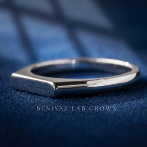 Custom engraved signet ring held between fingers with personalized inside band engraving visible.