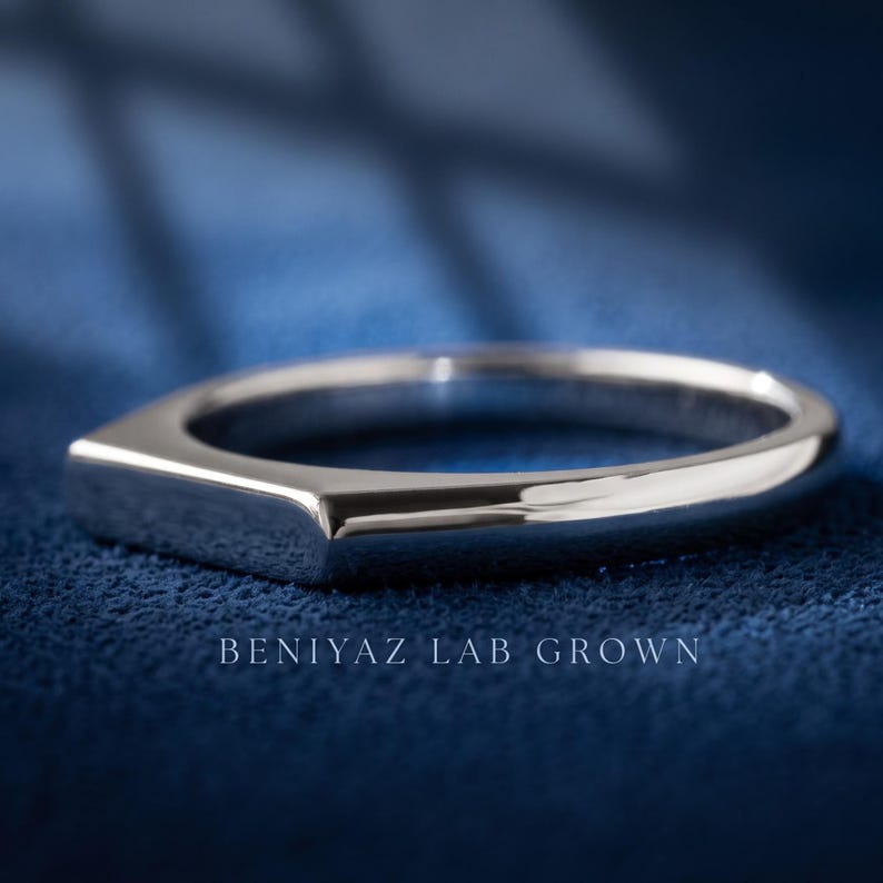 Custom engraved signet ring held between fingers with personalized inside band engraving visible.