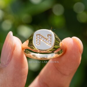 Hand holding custom letter signet ring featuring lab grown diamonds and polished yellow gold, personalized jewelry gift