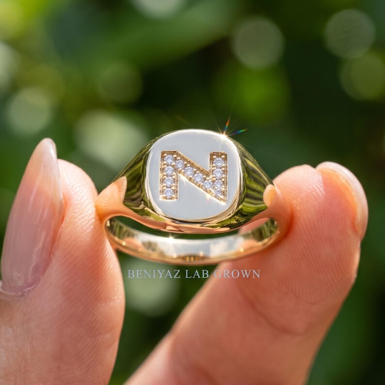 Hand holding custom letter signet ring featuring lab grown diamonds and polished yellow gold, personalized jewelry gift