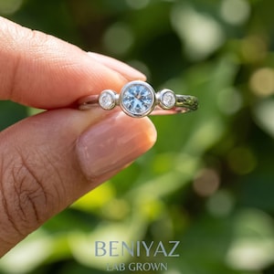 Side profile of a dainty three stone gemstone ring showing the smooth low-profile bezel-style settings.
