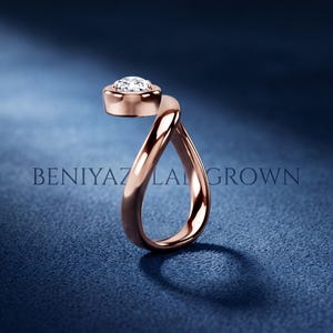 Top view of an asymmetric pear diamond ring with a modern bypass band and single lab grown diamond centre stone.