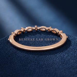 Inside view of marquise and round diamond band on blue background showing plain polished lower shank and stone set upper band