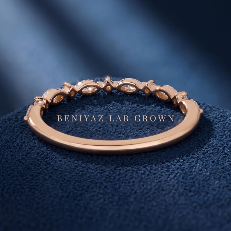 Inside view of marquise and round diamond band on blue background showing plain polished lower shank and stone set upper band