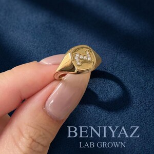 Close-up hand-held view of a personalized N diamond signet ring in 14K yellow gold, featuring sparkling lab grown diamonds and a polished custom initial face.