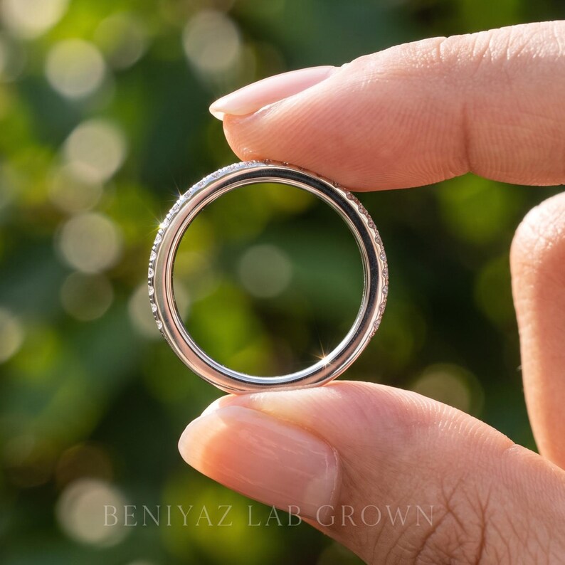 Rear view of a thin half eternity wedding band showing the smooth polished lower shank and round stone row across the upper half.