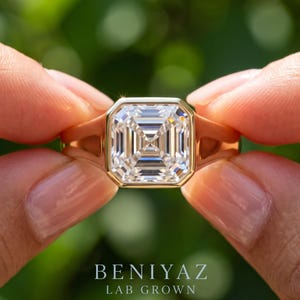 Lifestyle hand photo of 1.55 CT Asscher cut lab grown diamond engagement ring in 14K yellow gold, bezel set signet ring with IGI certified D color VVS1 diamond