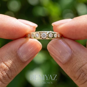 Close up celestial diamond band held by hand with seven star set lab grown diamonds arranged in a graduated starburst design
