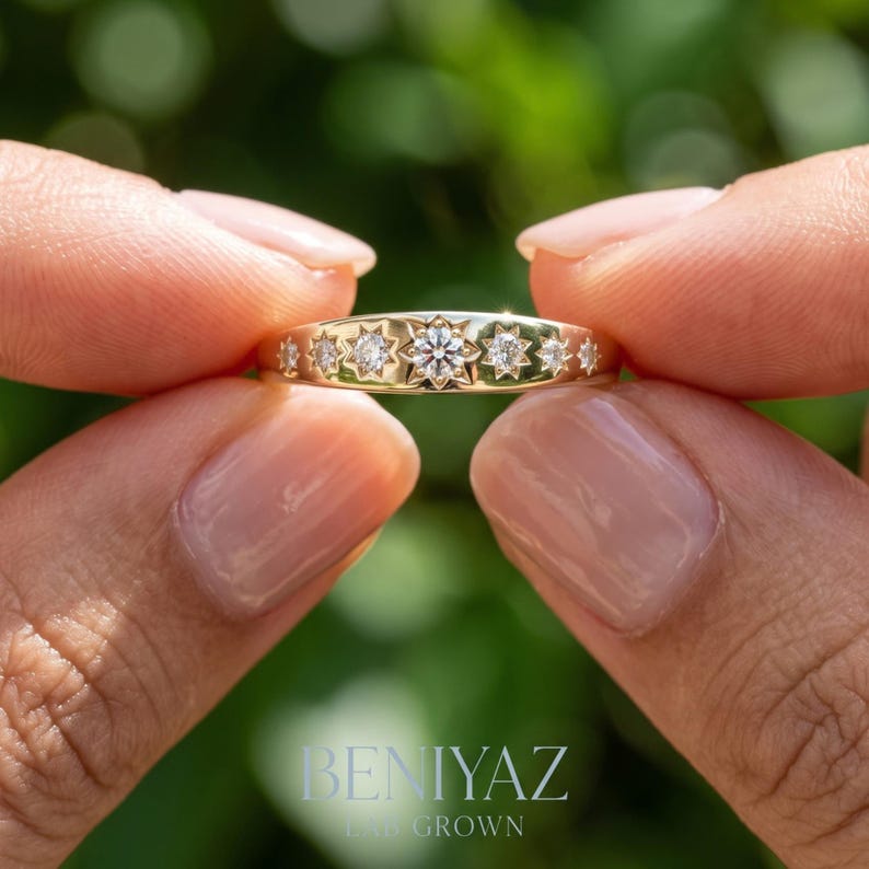 Close up celestial diamond band held by hand with seven star set lab grown diamonds arranged in a graduated starburst design