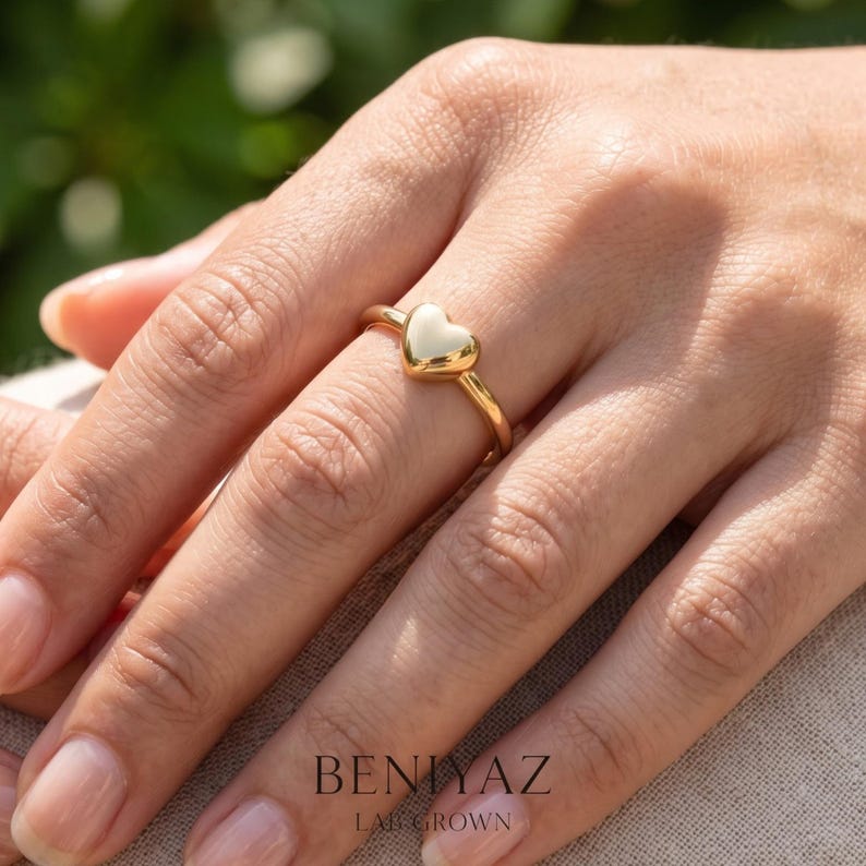 1. Lifestyle view of puffy heart ring worn on finger, a dainty stackable love ring and meaningful gift for her.