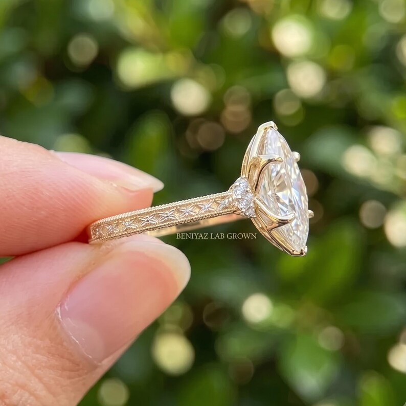 Rear view of a yellow gold marquise engagement ring showing the band, raised diamond setting and decorative pave shoulders.