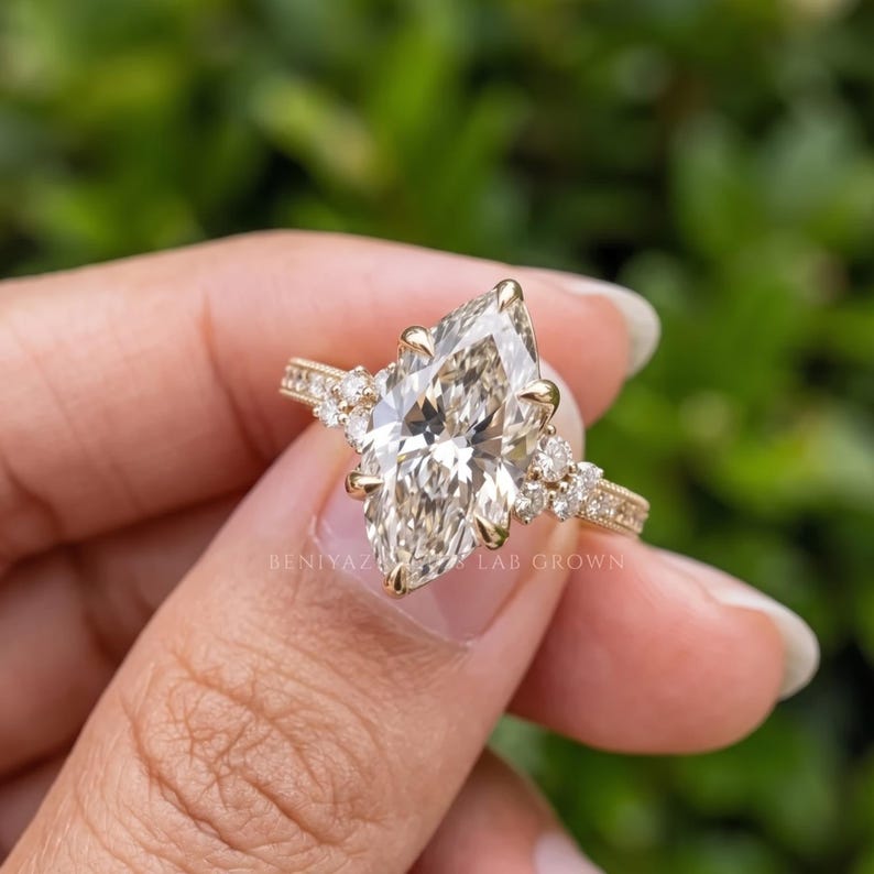 Hand held front view of a 3 carat marquise lab grown diamond engagement ring showing the elongated centre stone and ornate band.