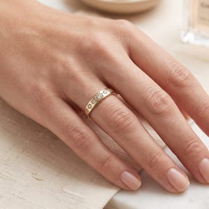 Lifestyle hand wearing a delicate starburst diamond ring with seven graduated lab grown diamonds and celestial gold band