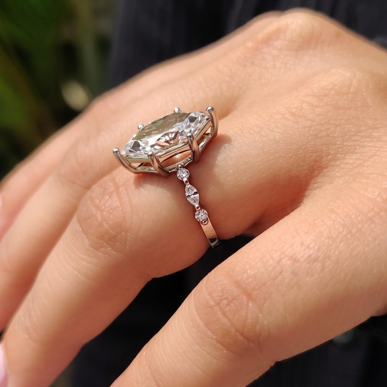 Close up of dutch marquise cut lab grown diamond ring with six prongs and marquise and round diamond accents on white gold band