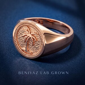 Rose gold vermeil palm tree signet ring shown on blue background with round medallion face, rope-style border and polished tapered shank