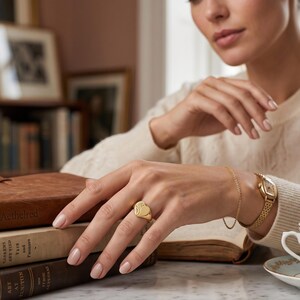 Woman wearing a heart shaped signet ring with vintage floral engraving, styled as a delicate ladies statement ring