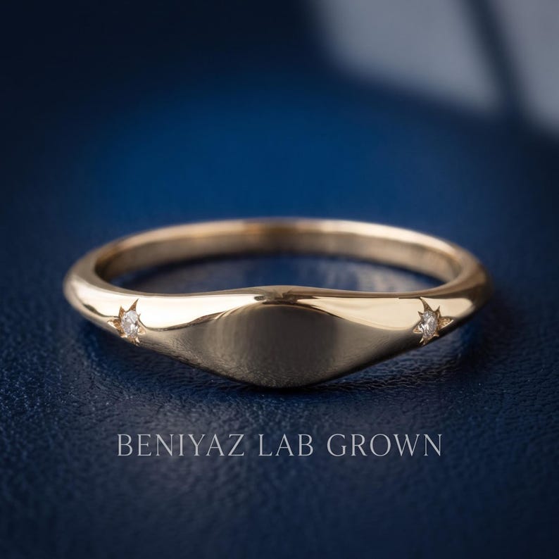 Top angled view of a minimalist yellow gold signet ring showing the slim tapered shank and smooth polished face.
