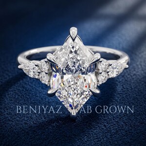 White metal marquise lab grown diamond engagement ring on blue velvet with symmetrical side stone clusters