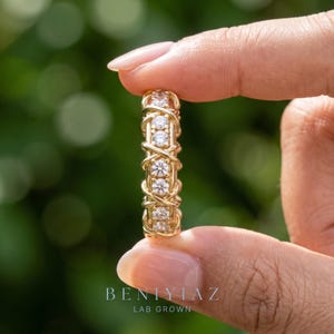 Hand-held vertical view of a lab grown diamond eternity band showing the repeating criss-cross structure around the complete ring.