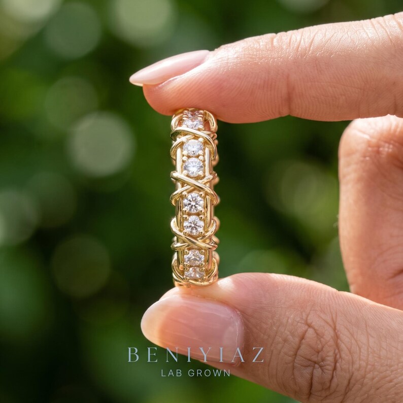 Hand-held vertical view of a lab grown diamond eternity band showing the repeating criss-cross structure around the complete ring.