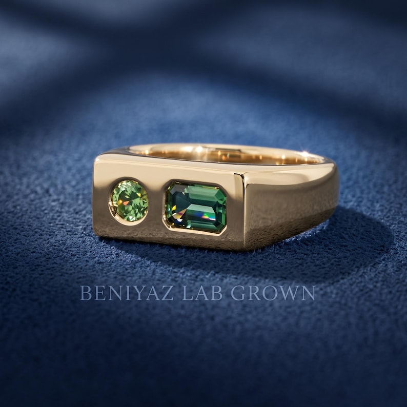Front view of a teal and green sapphire signet ring with emerald cut and round stones set into a wide flat top geometric gemstone ring