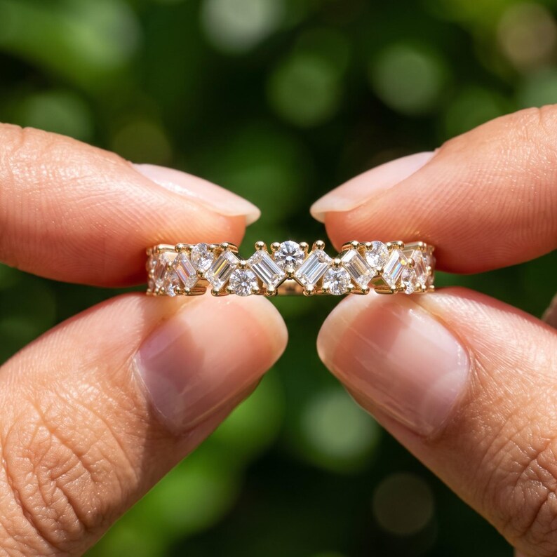 Close up hand view of a baguette lab grown diamond wedding band with a half eternity cluster setting, elegant gold stacking ring for anniversary or wedding