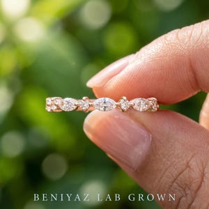Close up of dainty lab grown diamond band with alternating marquise and round brilliant diamonds held between fingers