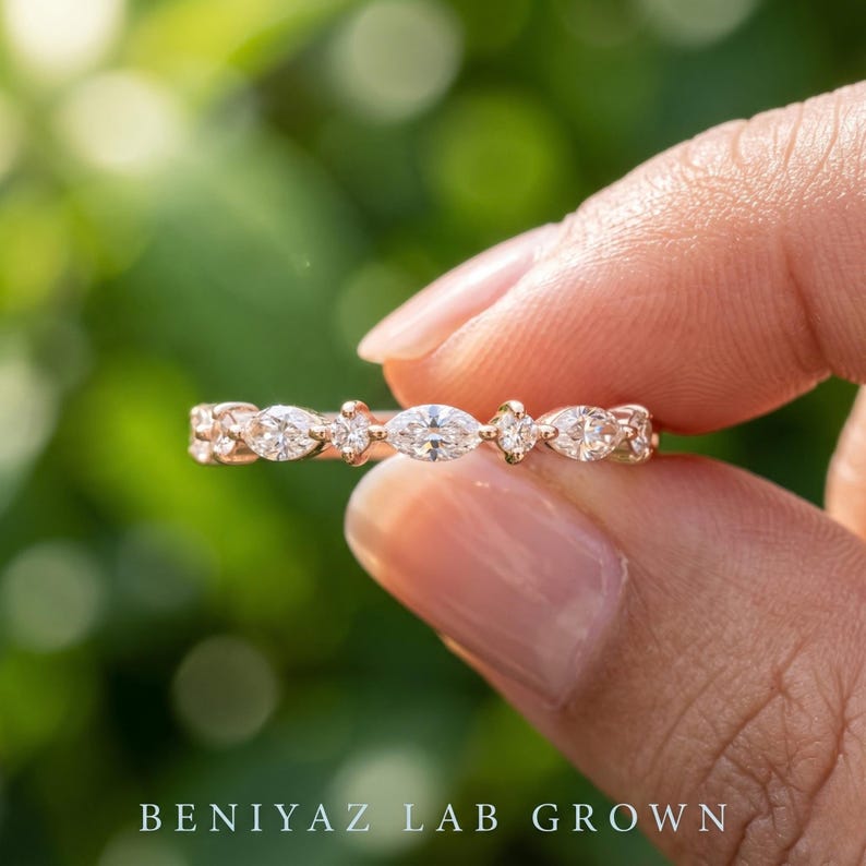 Close up of dainty lab grown diamond band with alternating marquise and round brilliant diamonds held between fingers