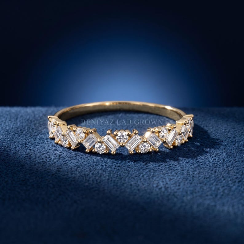 Curved lab grown diamond wedding band in white gold with round and emerald cut stones on deep blue background
