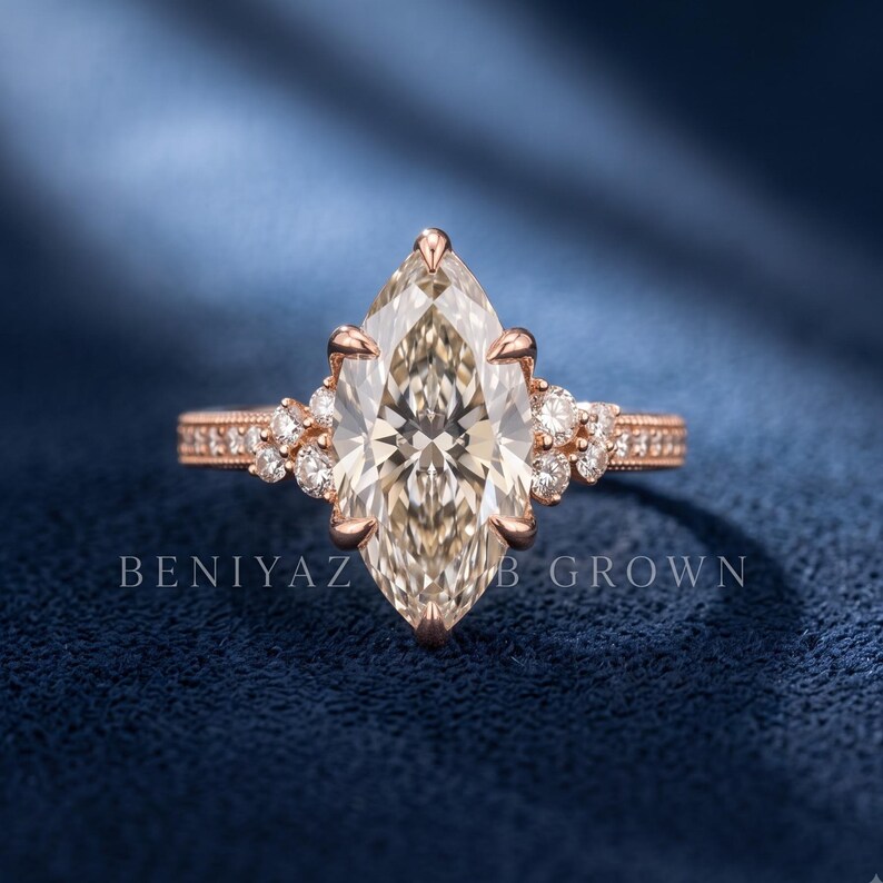 Close up of a marquise lab grown diamond engagement ring held outdoors, showing the large centre diamond and round side accents.