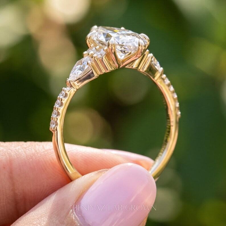 Full side profile of a marquise diamond ring held upright outdoors. The raised gemstone setting, intricate open gallery, decorative gold tone shoulders and smooth lower shank are clearly visible.