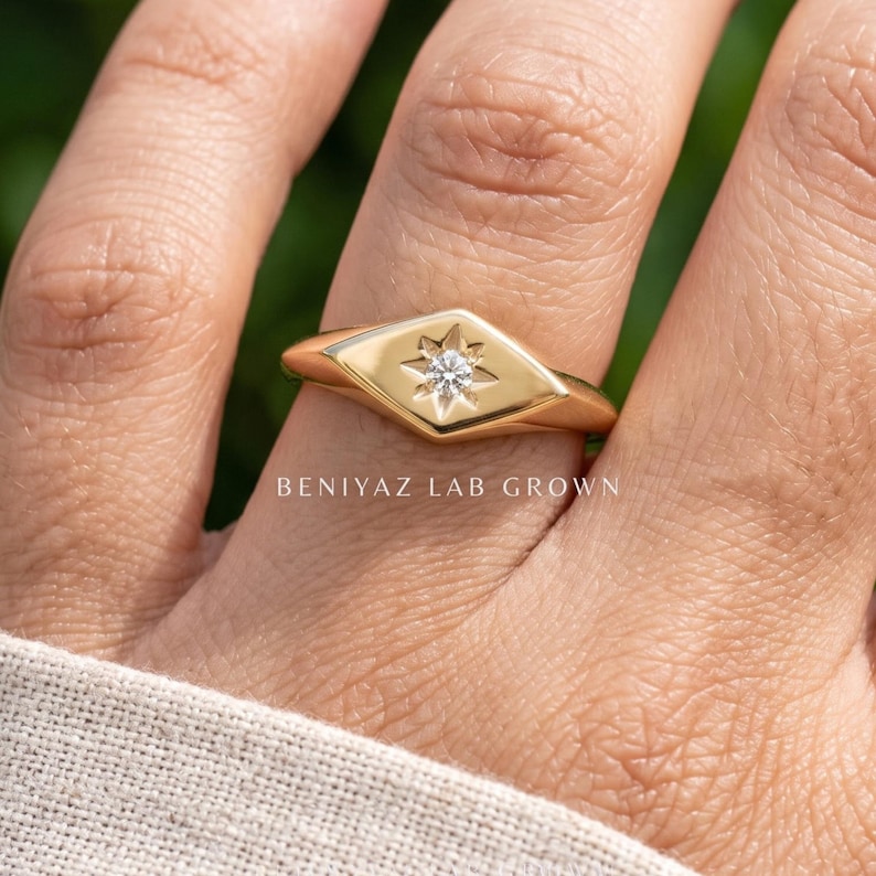 Signet ring women style worn on hand, featuring a single round lab grown diamond in a celestial star setting.