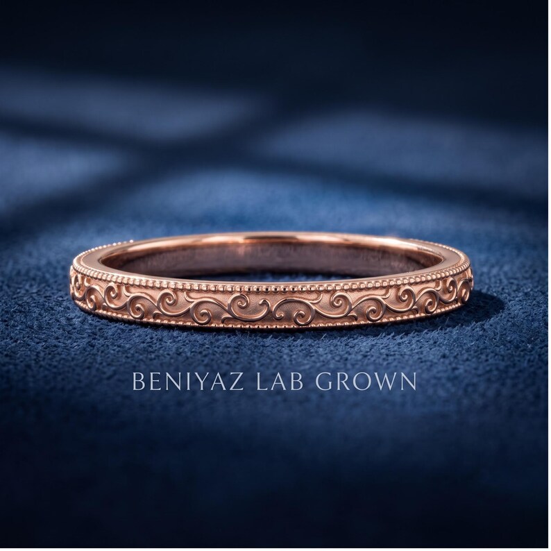 Rose gold scroll engraved milgrain wedding band in close view, vintage inspired slim stacking ring, delicate bridal band with ornate pattern.