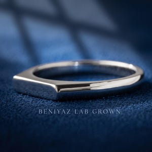 Personalized bar signet ring held by hand, showing the inside band engraving and polished silver tone finish.