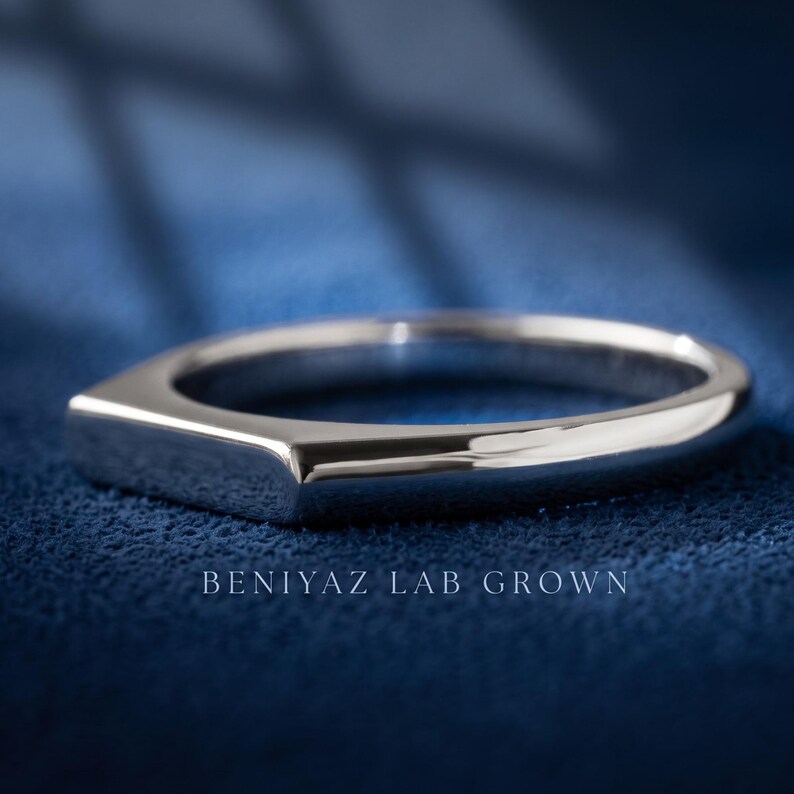 Personalized bar signet ring held by hand, showing the inside band engraving and polished silver tone finish.