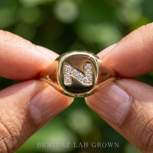 Side hand view of yellow gold initial signet ring with lab grown diamond accents, modern personalized statement ring design