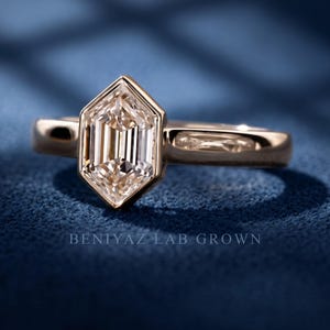 Angled studio view of a geometric hexagon lab grown diamond engagement ring featuring a step cut center stone and bezel-style setting.