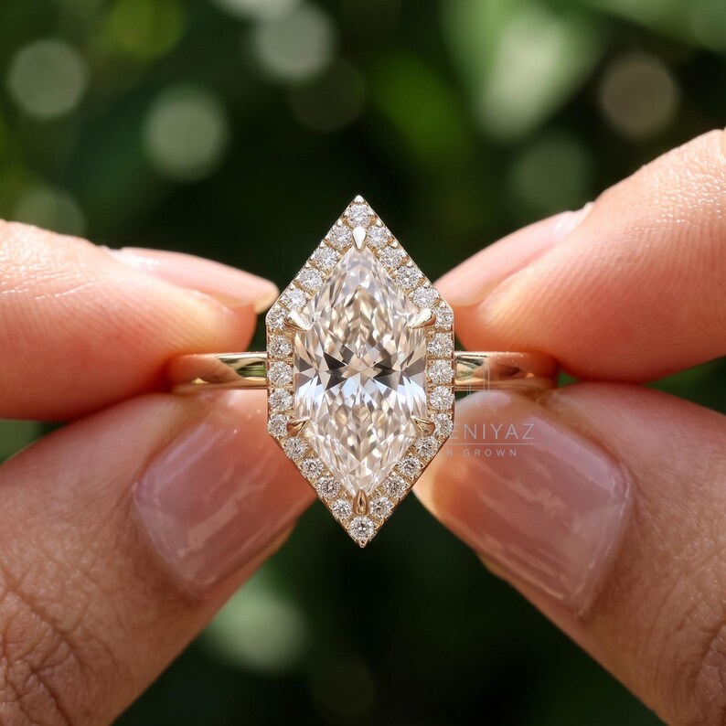 Hand held front view of a Dutch marquise lab grown diamond engagement ring surrounded by a geometric round diamond halo.